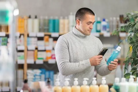 Young man scanning qr code of mouthwash Foto stock