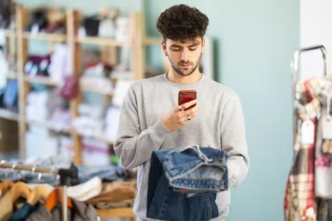 Young man scanning qr code of jeans in store Stock-Fotos