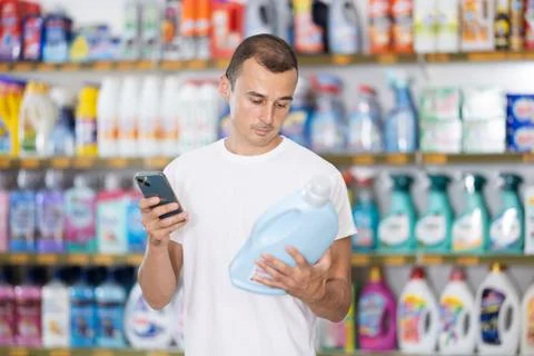 Young man scanning qr code for laundry detergent Foto stock