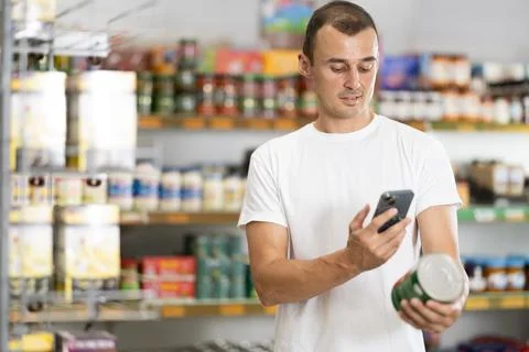 Young man scanning qr code for canned food Stock-Fotos