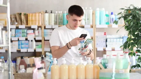 Young man scans the barcode of a toothbrush package in a pharmacy. Guy takes a Stock Footage 319991514
