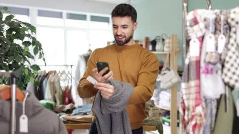 Young man scans qr code of sweater in store Stock Footage 332739024