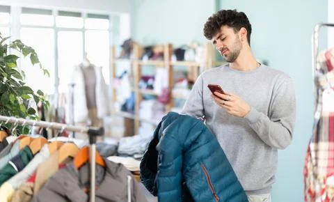 Young man scans qr code of down jacket in store Foto stock