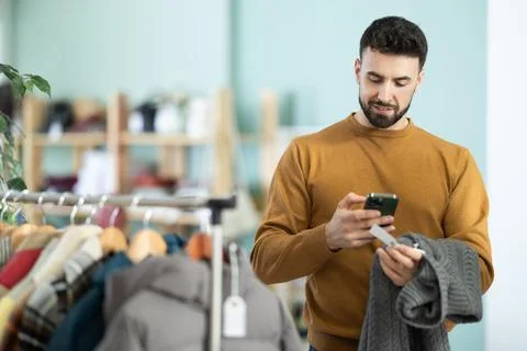 Young man scans qr code of sweater in store Foto stock