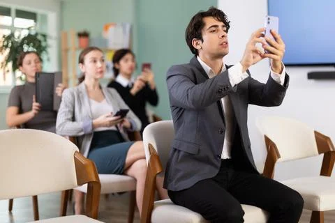 Young man scans QR code or takes photo of presentation in meeting room Foto stock