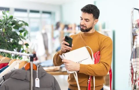 Young man scans qr code of womens handbag in store Stock-Fotos