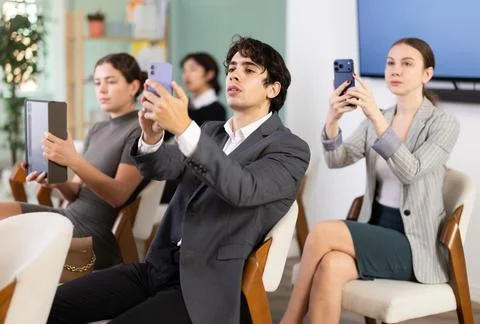 Young man scans QR code or takes photo of presentation in meeting room 스톡 사진
