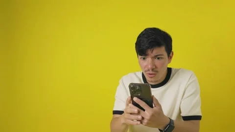 Young man with a scared expression while looking at his cell phone on a yel.. Stock Footage 311829563