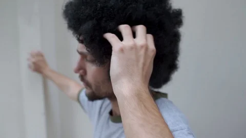 Young man scratching his head and fluffy curly black hair 動画素材 109293058