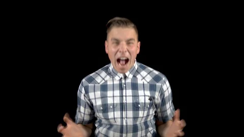 The young man is screaming. A man screams strongly in a shirt on a black Stock Footage 122256103