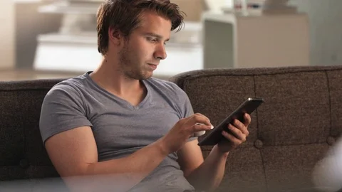 Young man scrolling on his tablet Stock Footage 78611716