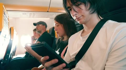 Young man scrolling smartphone with seat belt fastened on airplane. Other Vidéo 342334416