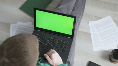 Young man scrolling through websites on his laptop with green screen Stock Footage 142742791