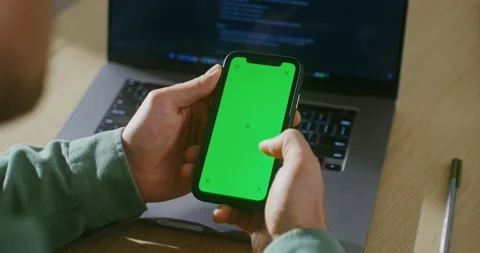 A young man scrolls the green screen of a mobile phone, copy space Stock Footage 167269500