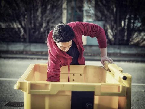 Young man searching inside garbage bin for stuff Stock Photos