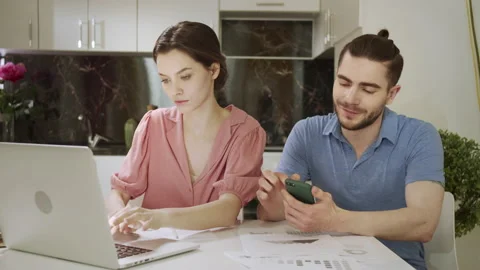 A young man is searching through the Internet while his wife is working at home Stock Footage 155786642