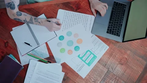 Young man searching through textbook and notes, writing on the laptop Stock-Footage 164374652