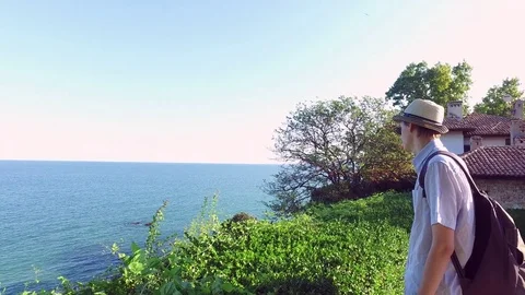Young man by the seaside admiring the stunning view on a sunny summer day Stock Footage 71966596