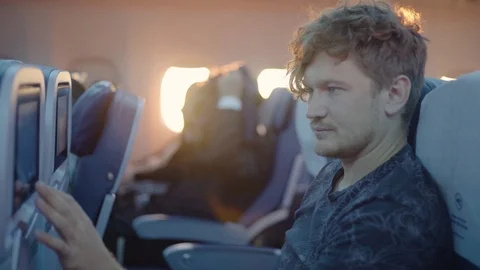Young man seat in an airplane using the touch screen Vídeos de archivo 94400063