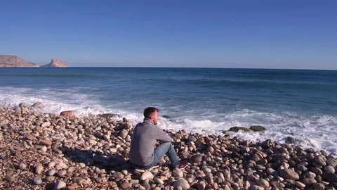 A young man seating on the beach. Stock Footage 83233137