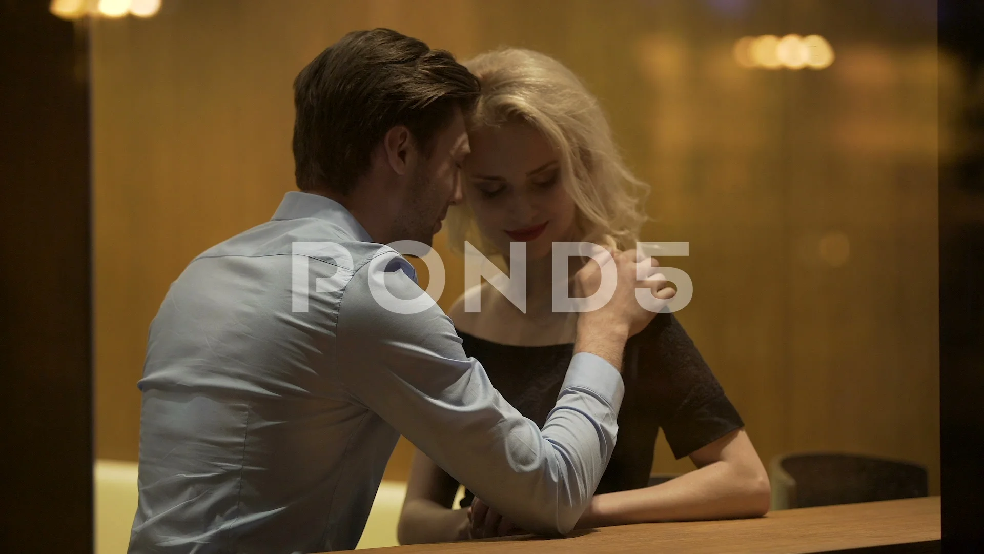 Young man seducing and petting beautiful blonde at lounge bar, evening time