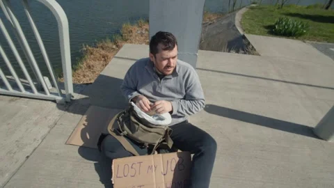 Young man seeks help by the water after job loss and homelessness Stock Footage 307197785