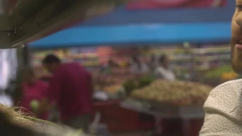 Young man selecting fresh vegetables and fruits at the supermarket Stock Footage