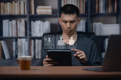 Young Man Selecting Icon on Digital Tablet in Modern Library Setting Stock Photos