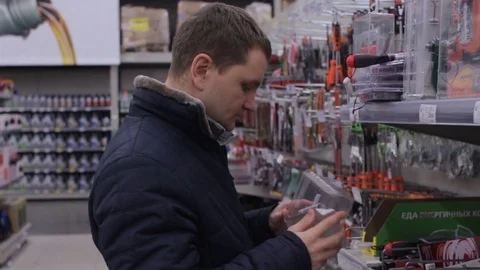 Young man selects tools in the hypermarket Stock Footage 74434137