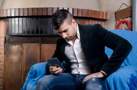 Young man sending sms at sofa Stock Photos