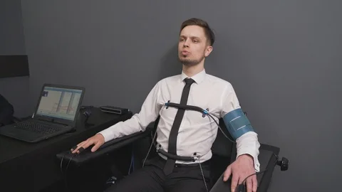 Young man in sensors checking with computer polygraph 動画素材 122627371