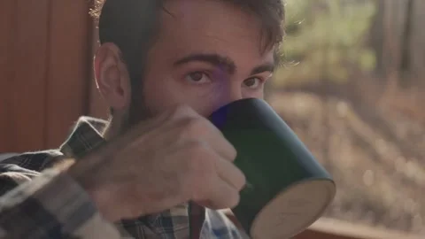 Young man sets down coffee mug, picks it up and drinks it Stock Footage 261107198