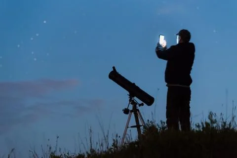 Young man sets up a telescope using a smartphone Stock Photos