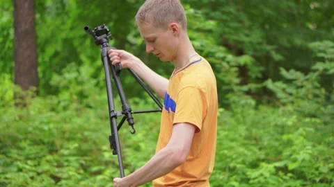 A young man sets a tripod for the camera. Stock Footage 92311974