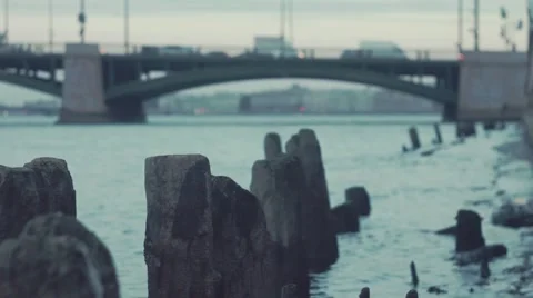 Young man setting fire a log sticking out of the water near the stone embankment Video stock 69036409