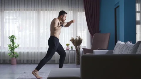 Young man shadowboxing at home to maintain his fitness and fitness Stock Footage 232277400
