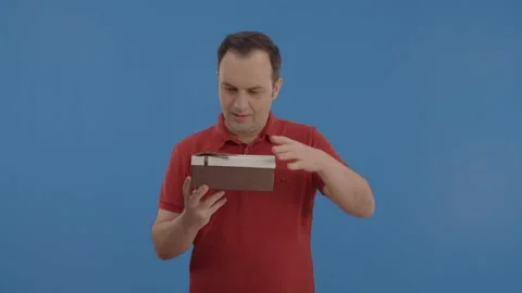 The young man shakes the gift, opens it and expresses that he likes it. Stock Footage 148260101