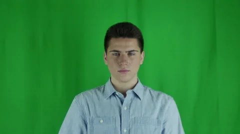 Young man shakes head in front of a greenscreen in a blue shirt Vidéo 58999133