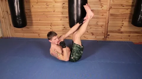 Young man shakes the press, lying on the mat in the hall of mixed martial arts. Stock Footage 61770132
