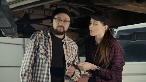 A young man shares the experience of servicing and repairing a car with a girl Video stock 104130550