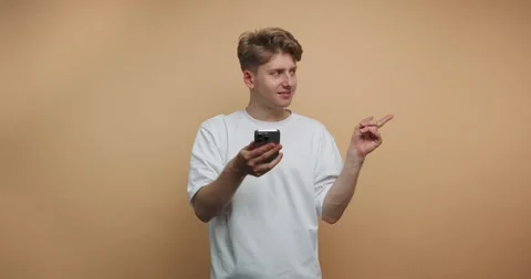 Young man shares thoughts while using phone in a simple studio setting duri.. Stock Footage 317328080