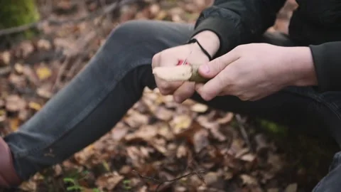 A young man sharpens and cleans a stick with sharp knife to prepare for the trip Stock Footage 142126389