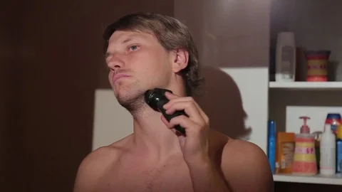 Young man shaving in front of the mirror. Stock Footage 76116650