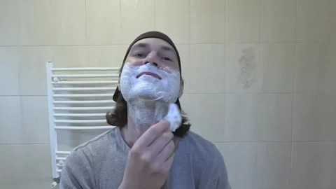 Young man shaving in front of a mirror with a classic razor Stock Footage 242284771