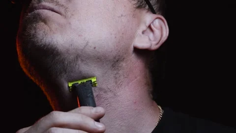 Young man shaving his face with a trimmer for shaving Video stock 308537857