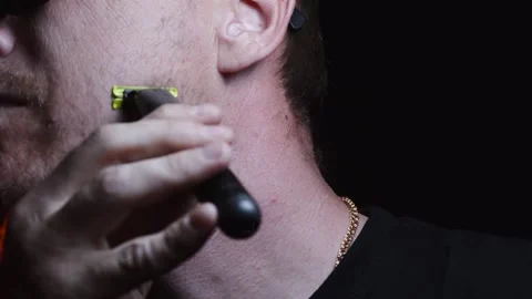 Young man shaving his face with a trimmer for shaving Video stock 308537869