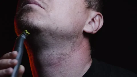 Young man shaving his face with a trimmer for shaving Video stock 308537879