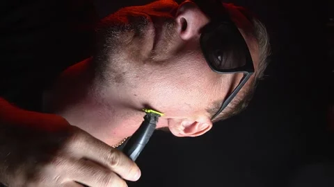 Young man shaving his face with a trimmer Stock-Footage 308538099