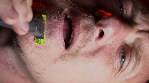 Young man shaving his face with a trimmer Stock Footage 308538105