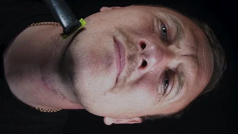 Young man shaving his face with a trimmer Stock Footage 308538120